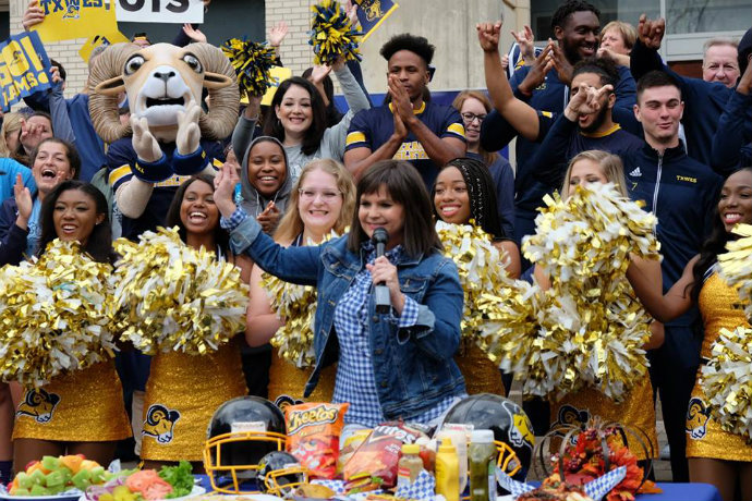 Photo of WFAA reporter Paige Smith during live broadcast of 'Good Morning Texas' from campus. Texas Wesleyan cheerleaders, staff and students are also pictured.