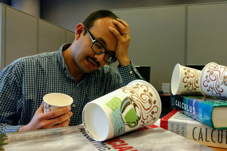 stressed student studying with books and coffee cups