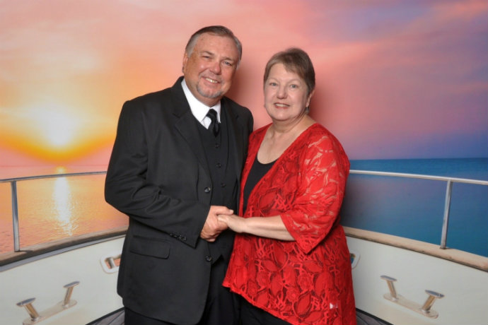 Photo of a man and woman in front of a cruise backdrop