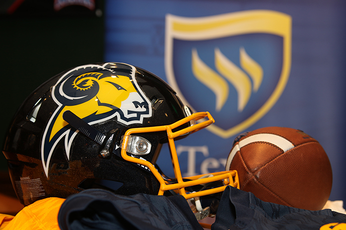 A Texas Wesleyan football helmet and football are displayed. The Texas Wesleyan shield is pictured in the background.