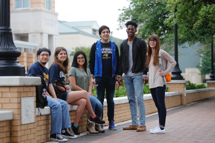 Students sit together in a group along Rosedale near Canafax Clock Tower and smile to the camera.