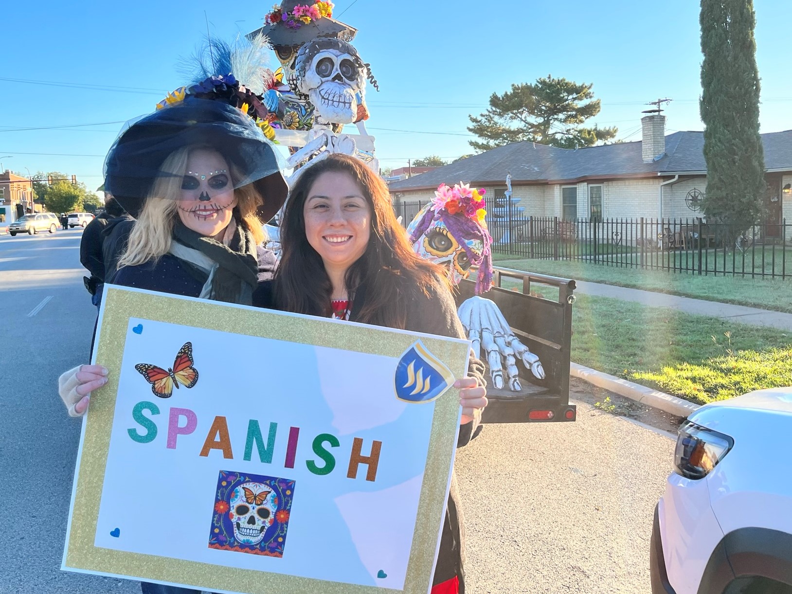 Dr. Amy Bell and a student pose in costume holding a sign that says 