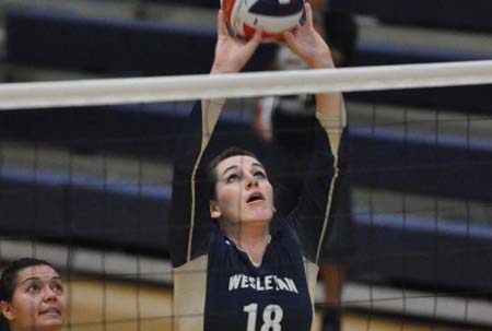 Volleyball player Katherine Rosenbusch spikes ball over the net