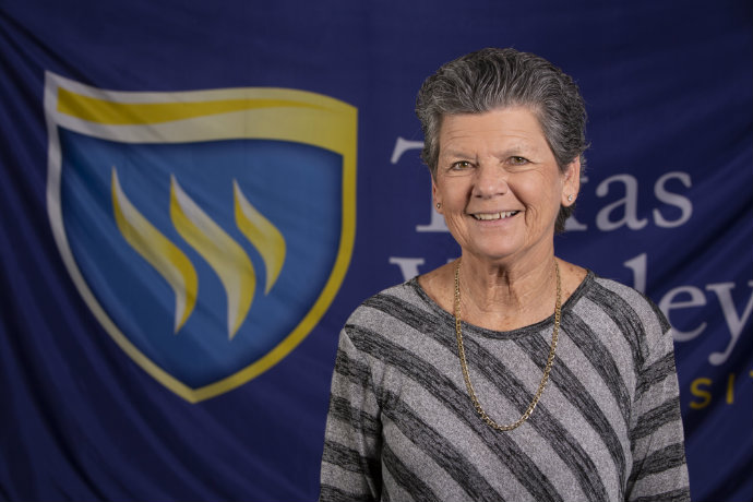 Photo of a man in a gray shirt in front of a Texas Wesleyan logo backdrop