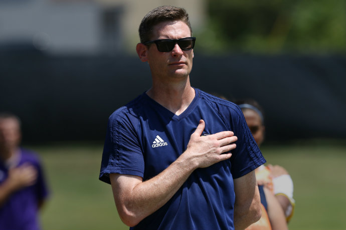 Head coach of Women's Soccer Josh Gibbs is pictured with his hand over his heart during the national anthem before a soccer match.