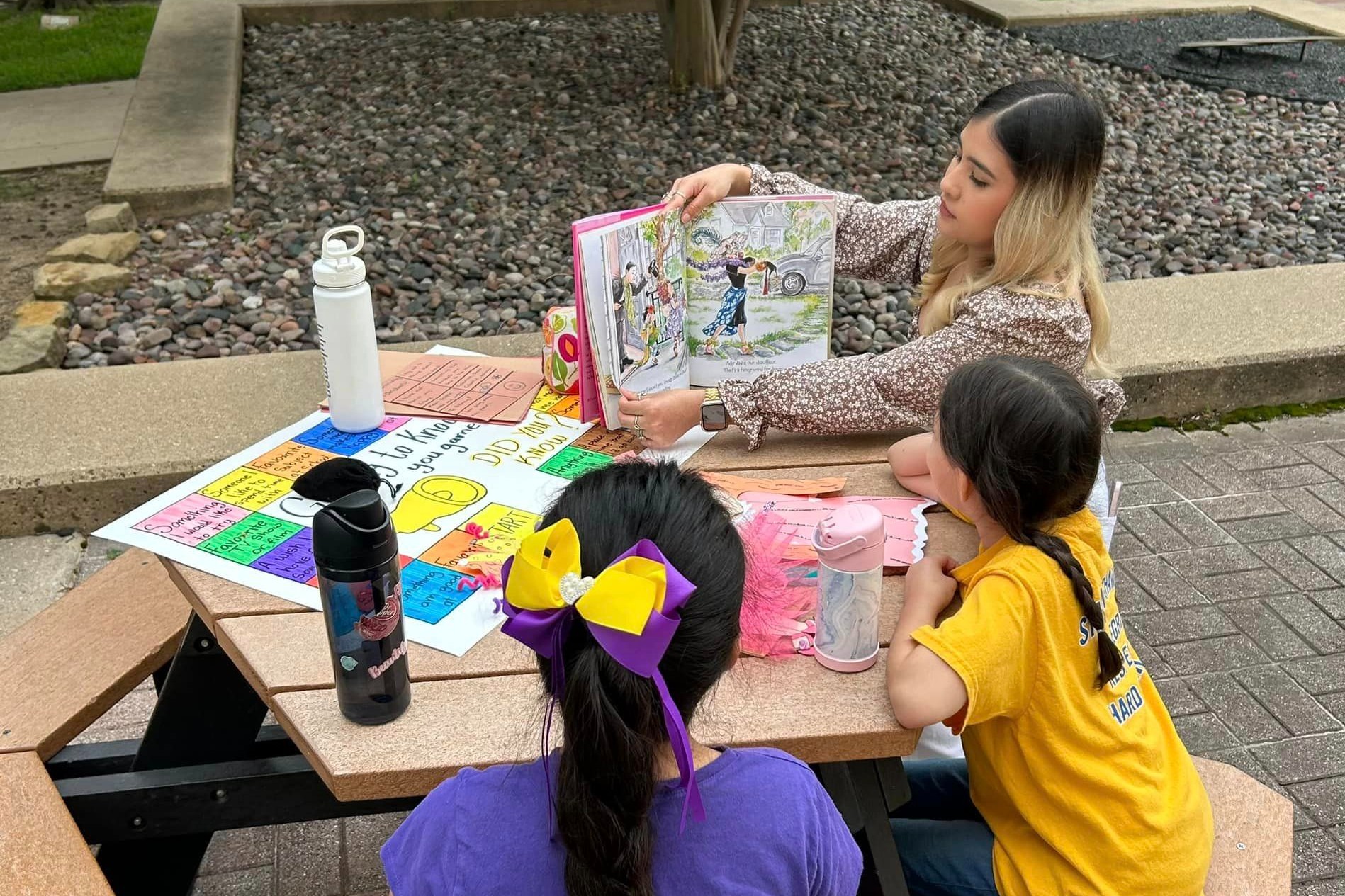 A female education student shows off a book to two young students