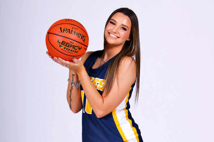 Peyton Foster smiles as she holds up a basketball