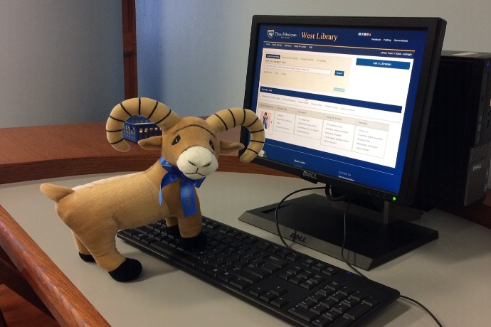 University Ram Mascot posing by a Library Computer