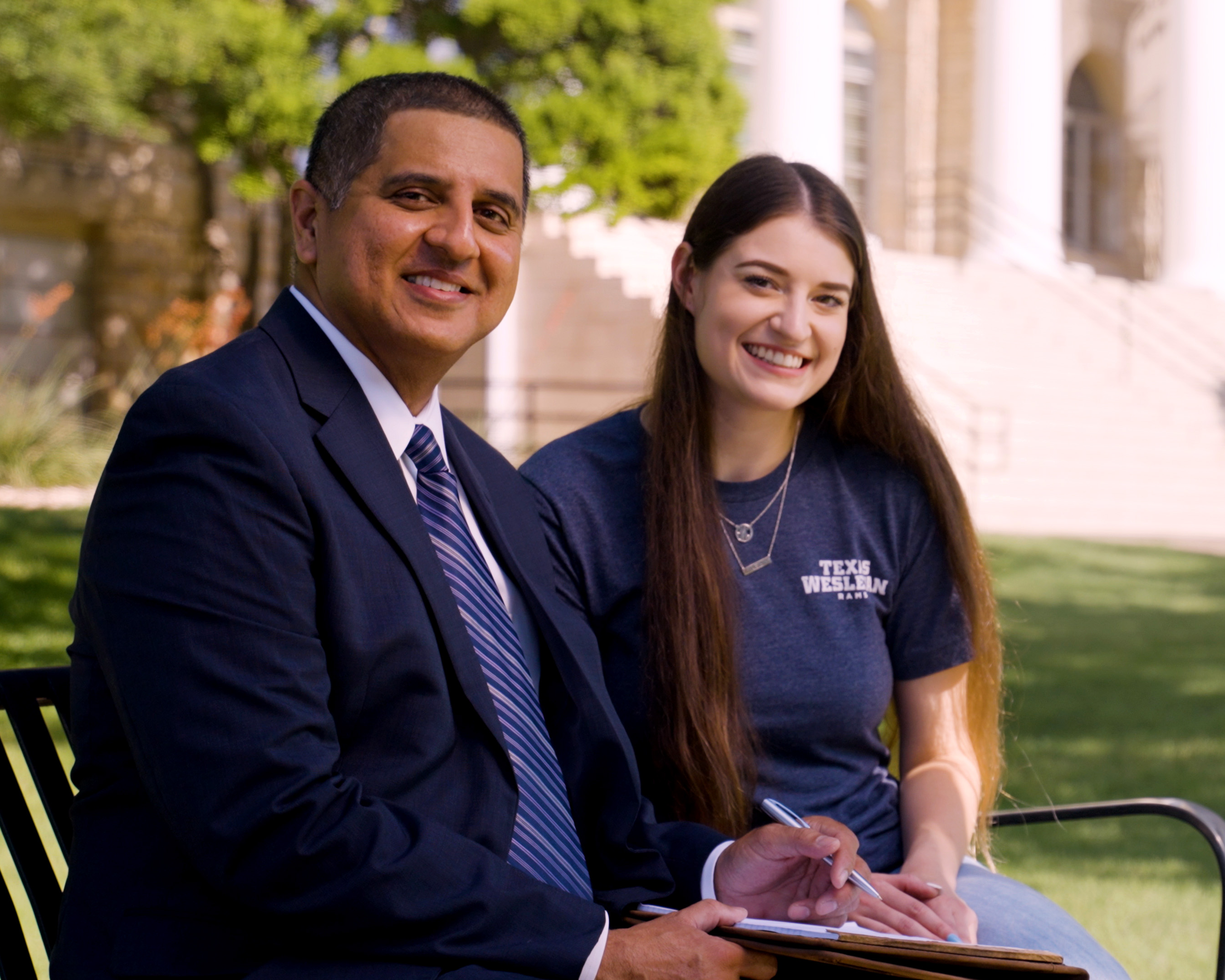 Teacher and student outside smiling on a bench