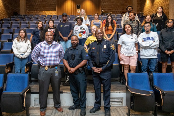 Three Fort Worth Police Officers pose with a group of students in a classroom
