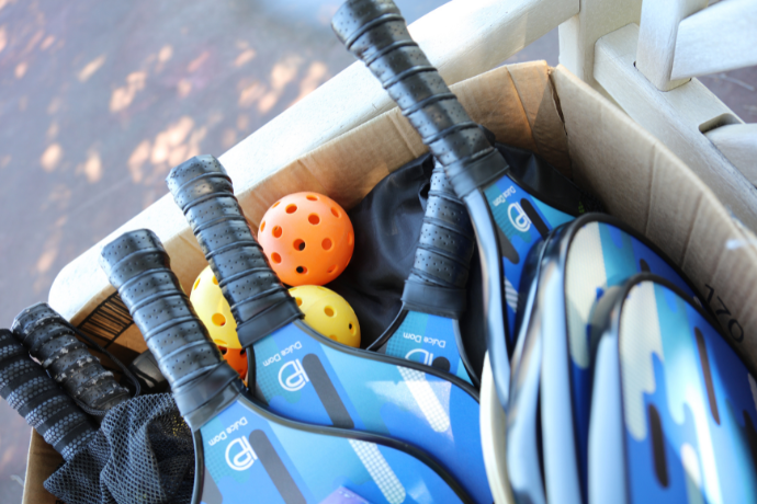 Pickleball Paddles & Pickleballs in a box on a bench.